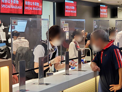 空港旅行代理店カウンターで沖縄渡航客に向けた沖縄で使える旅行系アプリ訴求リーフレットのサンプリング事例1